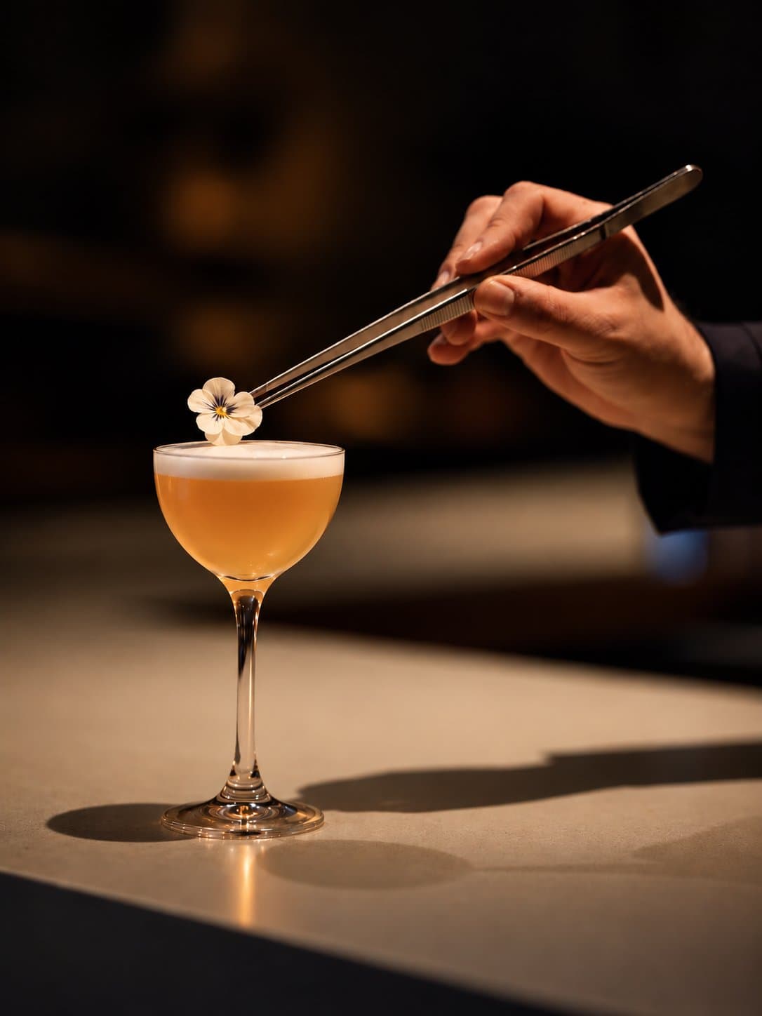 Mixologue déposant une fleur à la pince sur un cocktail